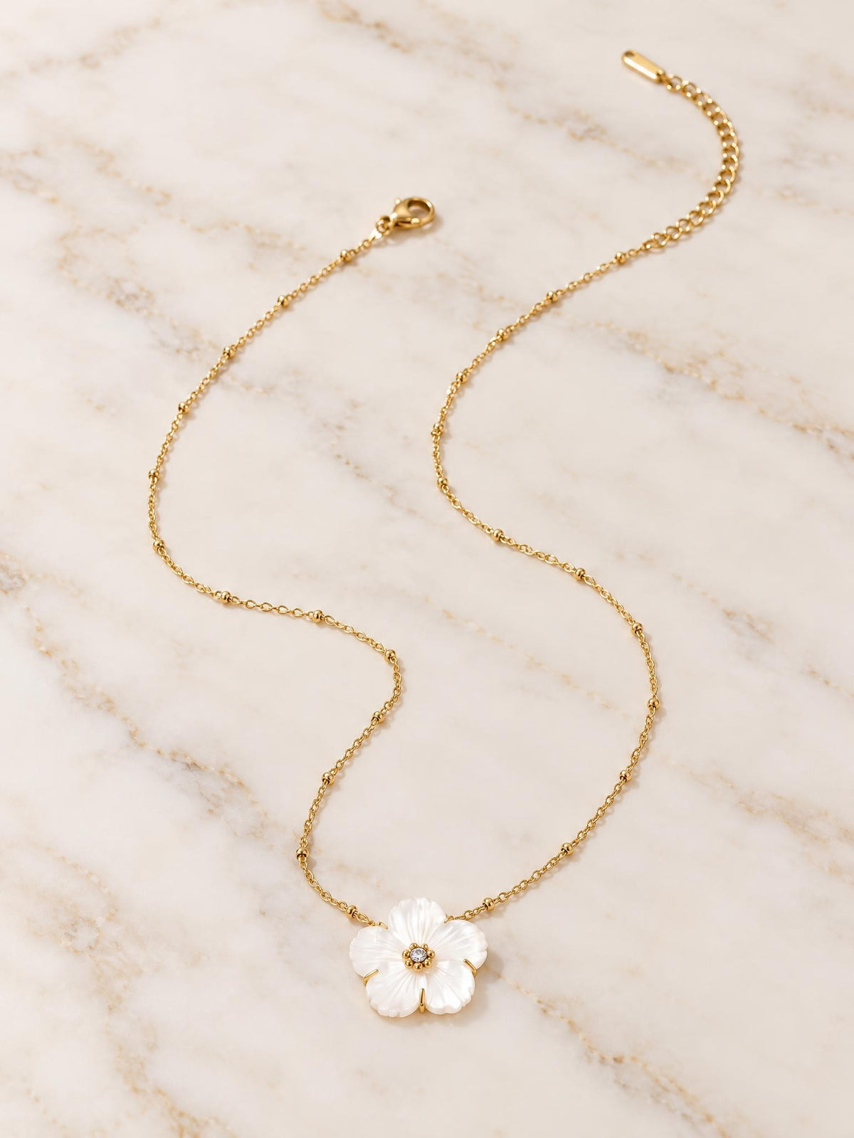 Collier Douceur porté dans un intérieur d'automne, bougie et fleurs séchées en arrière-plan
