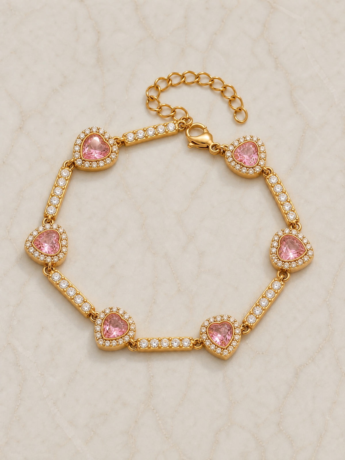 Bracelet Joséphine posé à plat sur marbre – pierres roses serties alternées avec des barrettes pavées de zircons, fermoir mousqueton et chaînette d'extension