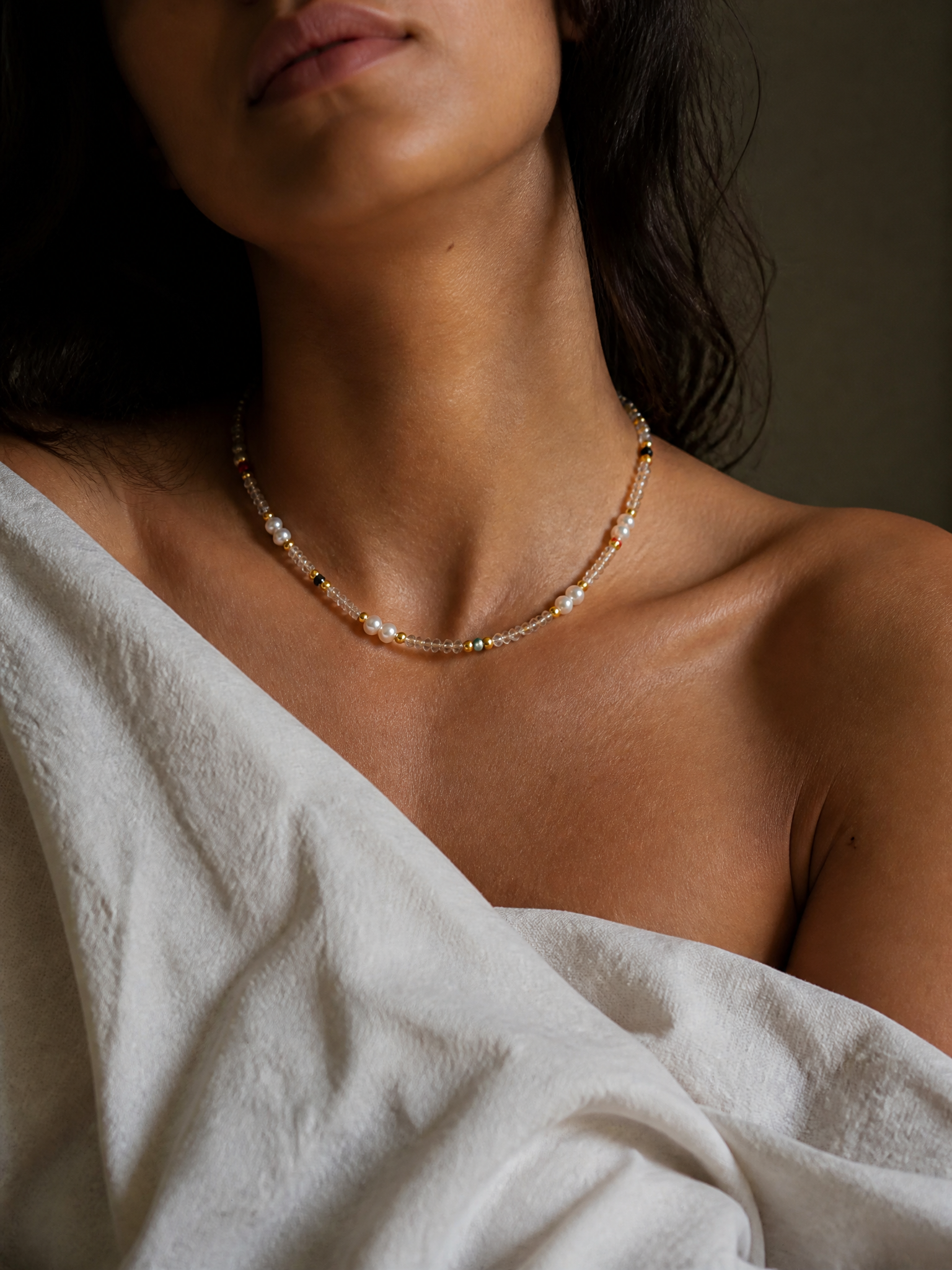 Collier Harmonia porté, gros plan sur la clavicule : perles d'eau douce et éclats rouge, vert et noir