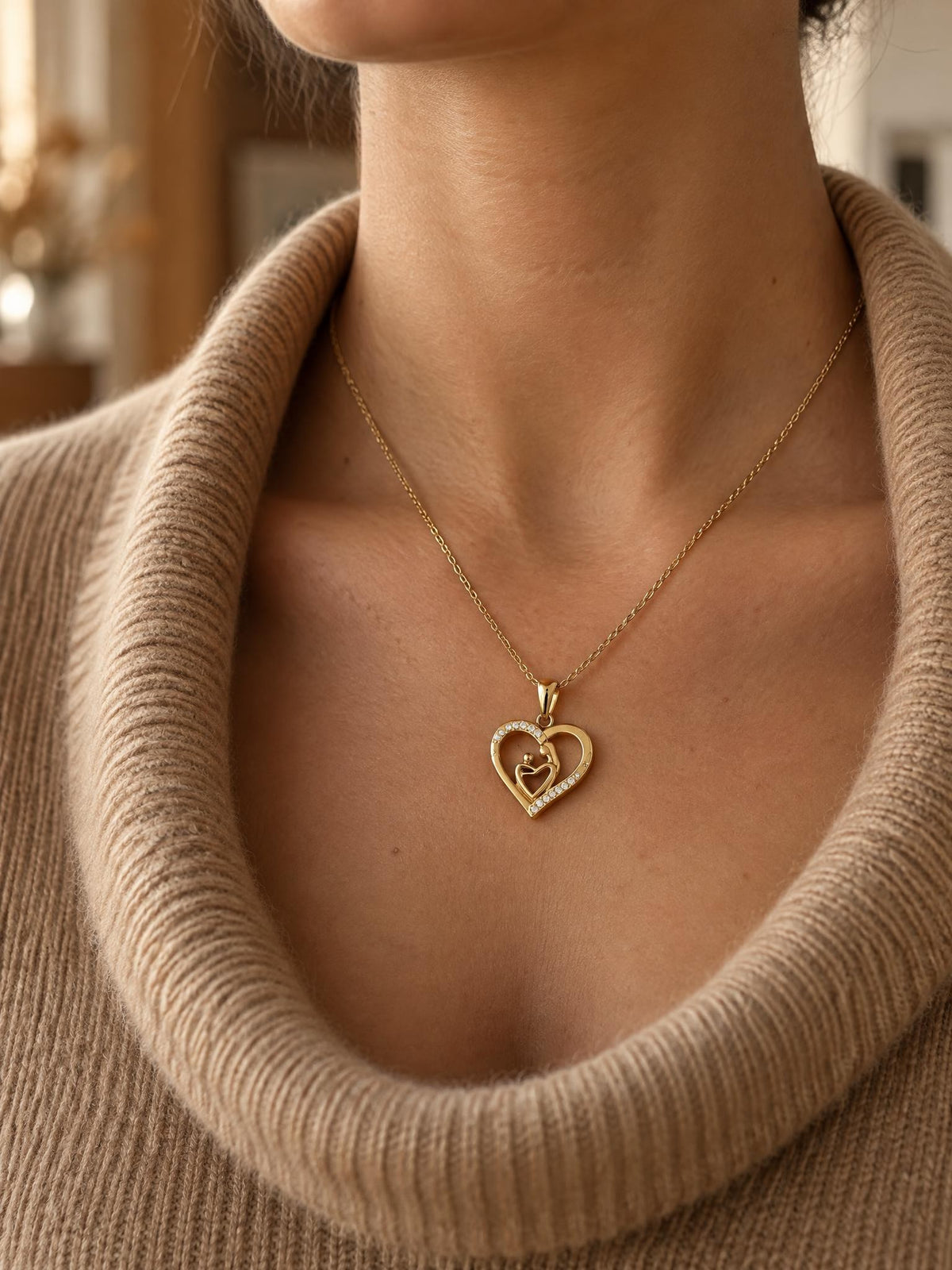 Femme portant le collier Maélie, pendentif cœur mère-enfant doré posé sous la clavicule, col roulé camel