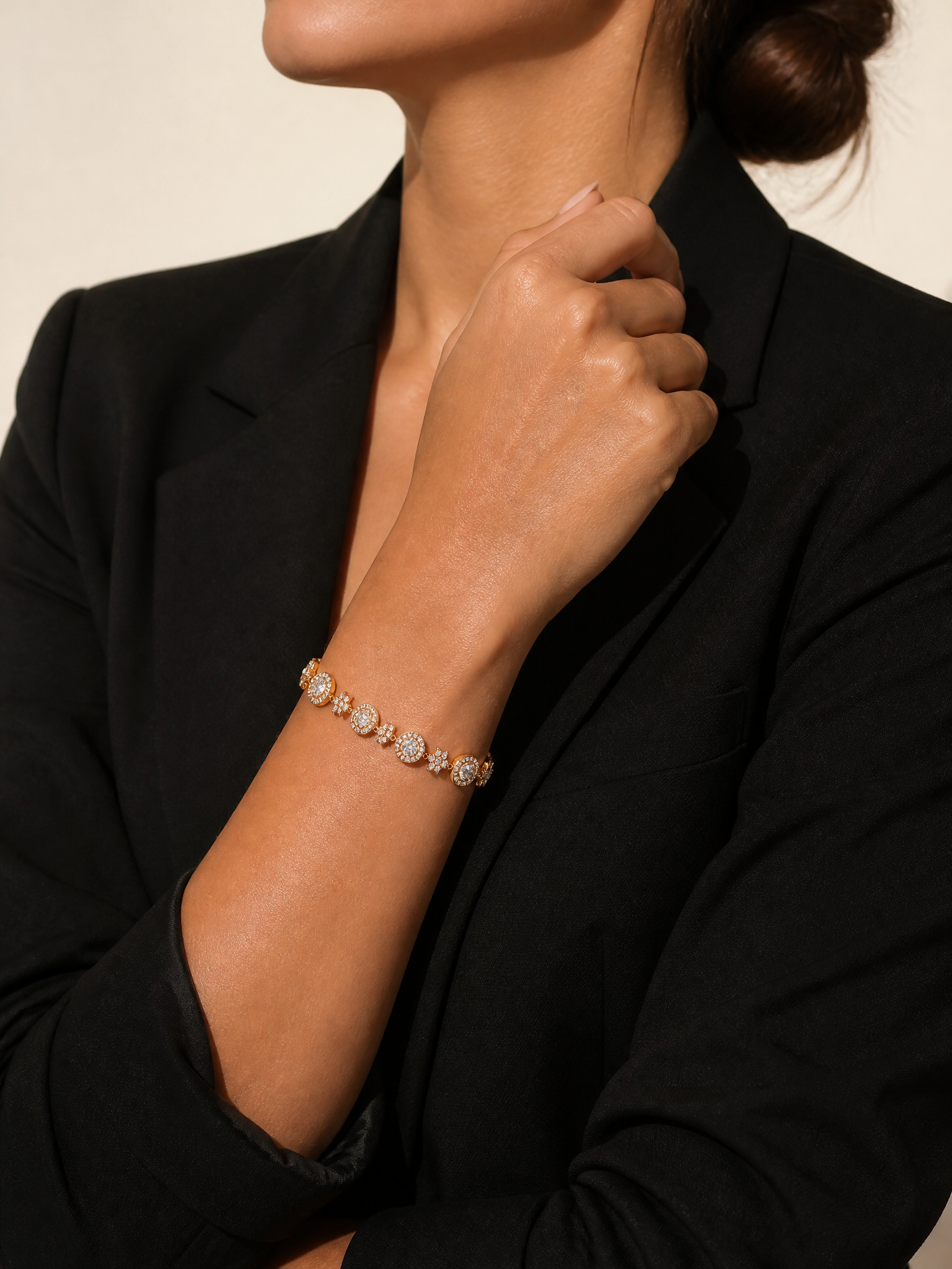 Femme en veste noire portant le bracelet Stella doré pavé de zircons au poignet