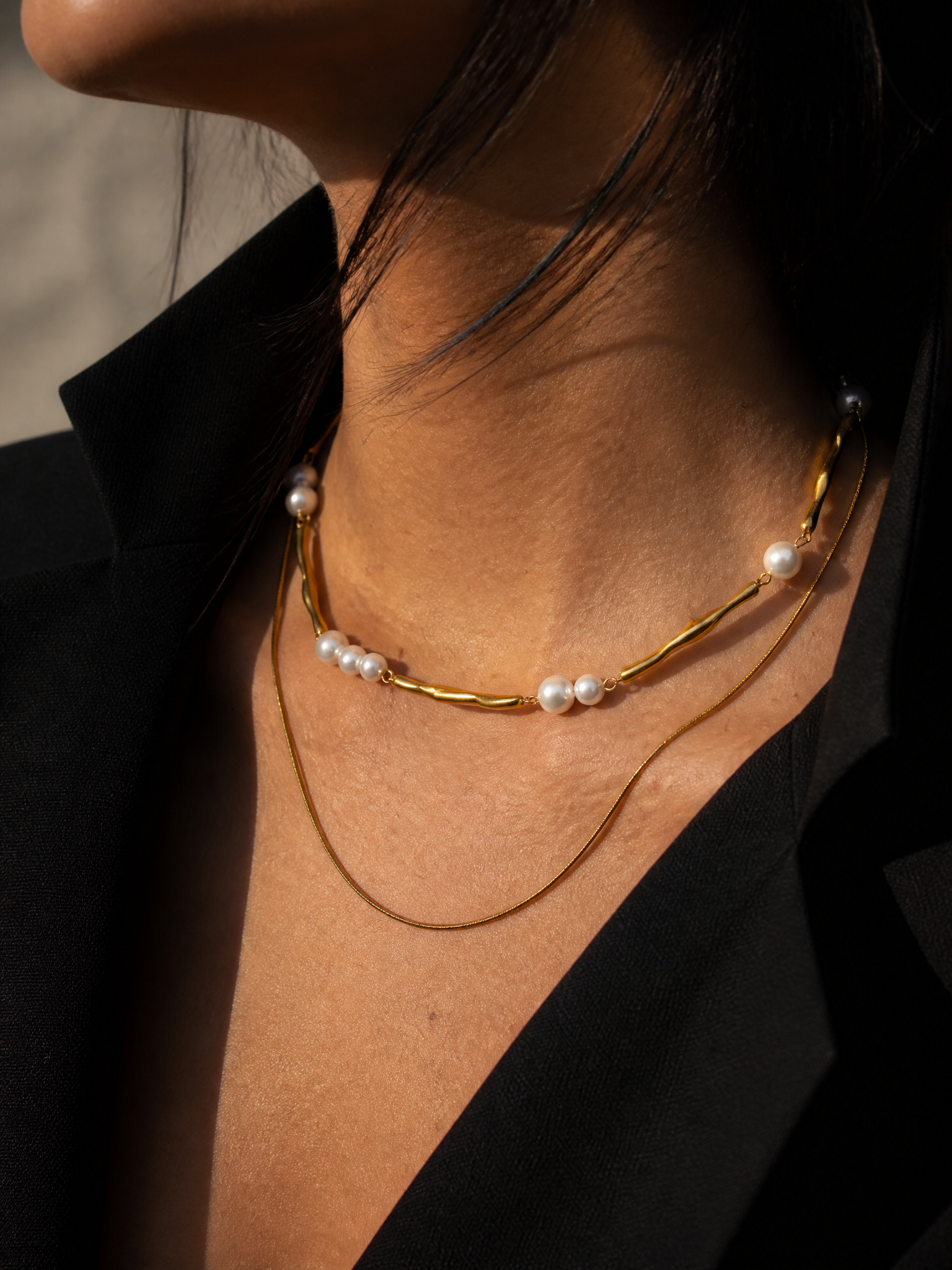Collier Dune porté, gros plan sur le décolleté : double rang doré et groupes de perles nacrées