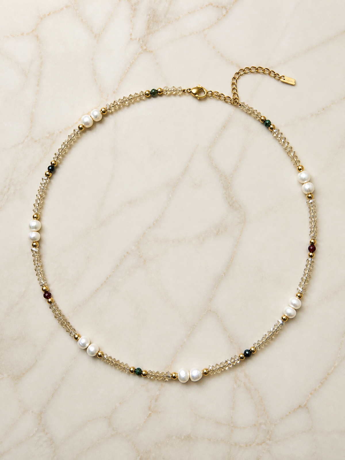 Collier Harmonia à plat sur marbre crème : cercle complet, fermoir doré et chaîne de rallonge