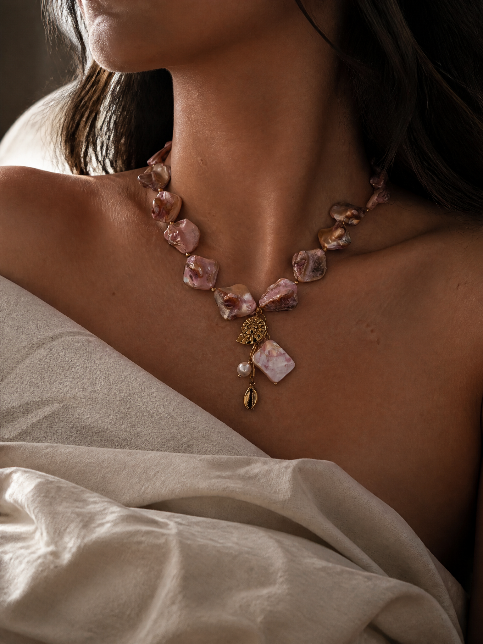 Collier Sirena porté : rang de grands pétales nacrés rose poudré et charms marins dorés