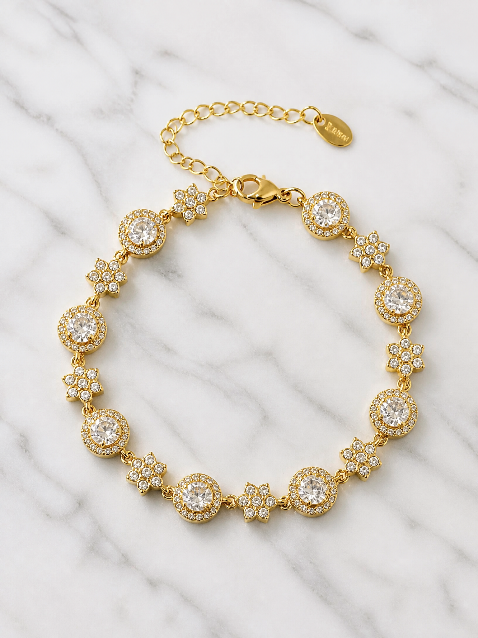 Bracelet Stella posé à plat sur marbre blanc – 8 solitaires et 8 fleurs pavées de zircons, fermoir mousqueton et chaînette d'extension