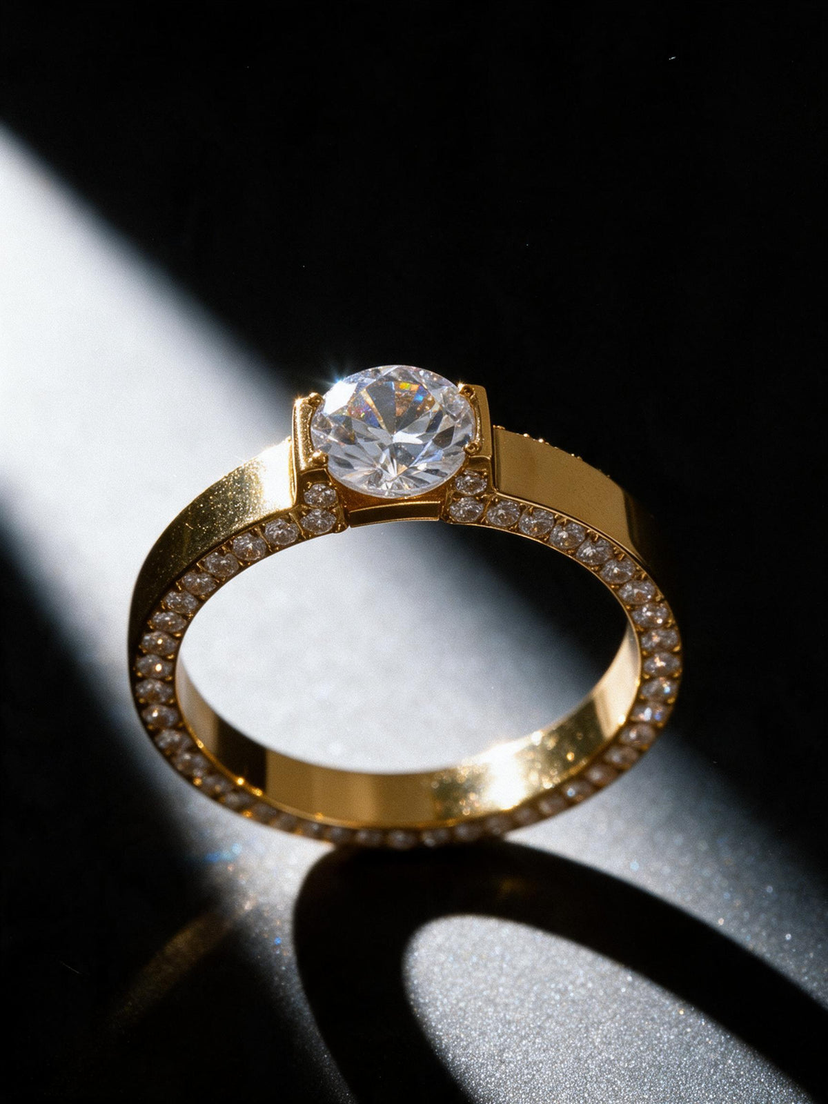 Bague Alma dorée sur fond noir – solitaire zircon, bande plate à arêtes pavées, acier inoxydable plaqué or 18K