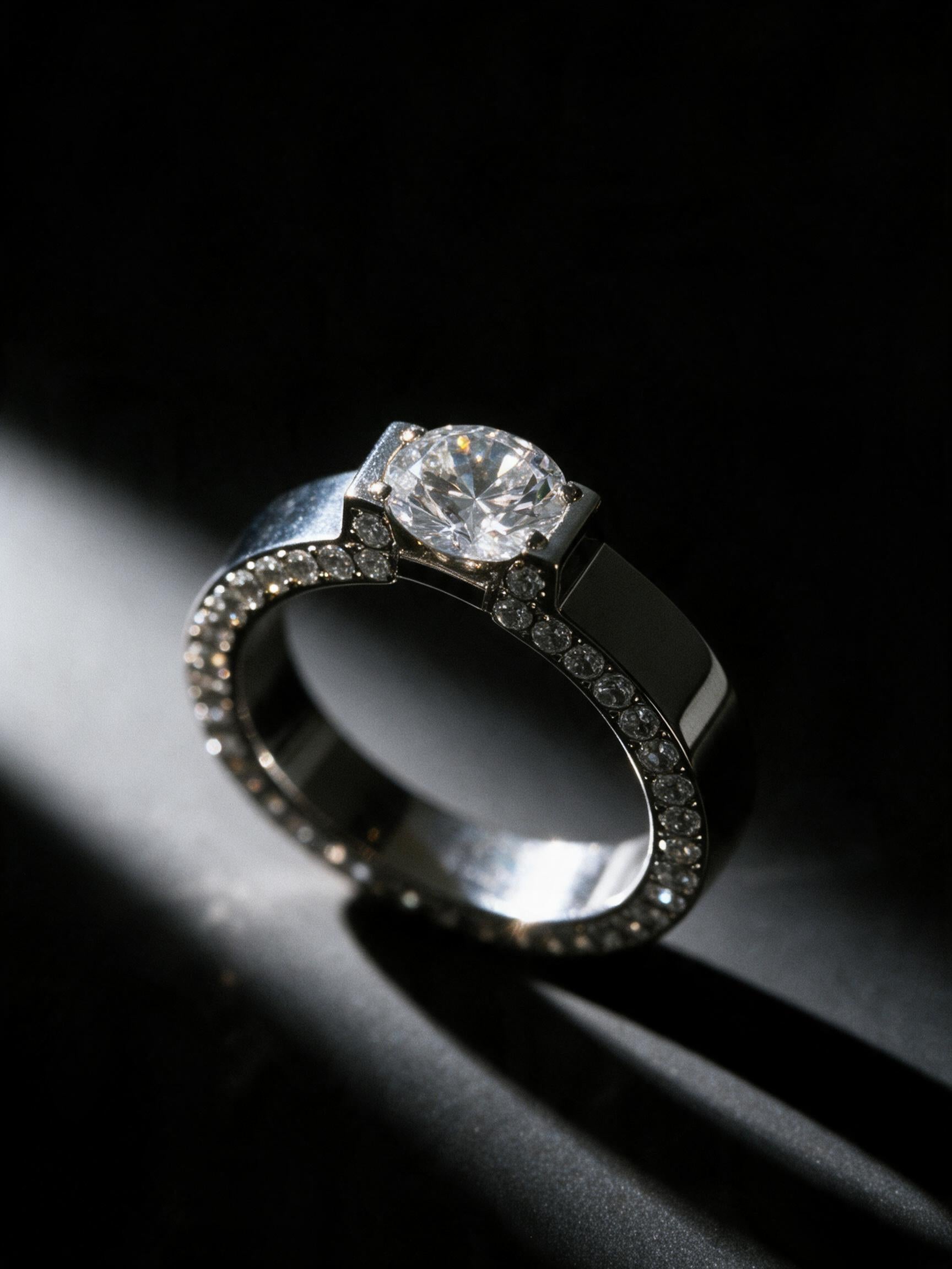 Bague Alma argentée sur fond noir – solitaire zircon, bande plate en acier inoxydable finition argentée