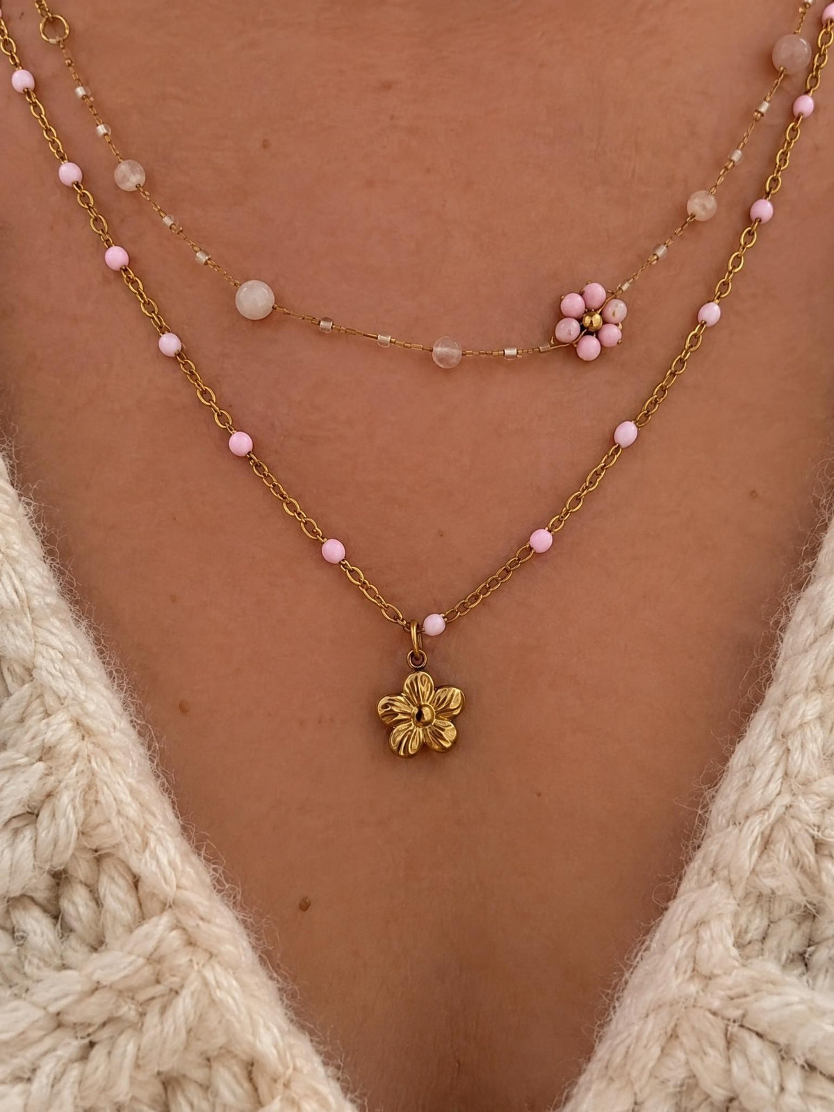 Gros plan sur la grappe de perles roses et le pendentif fleur doré du Collier Aurora