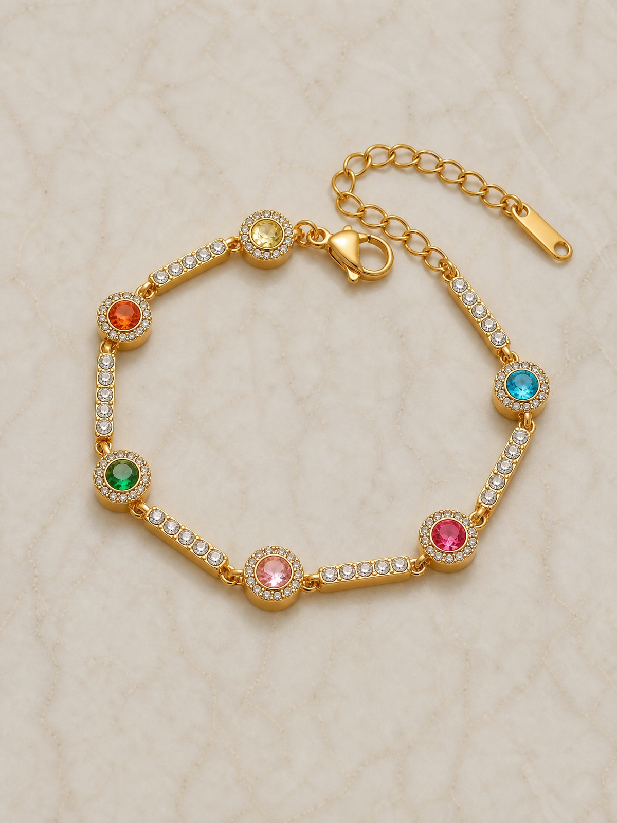 Bracelet Garance posé à plat sur marbre – six pierres multicolores serties alternées avec des barrettes pavées de zircons blancs, fermoir mousqueton