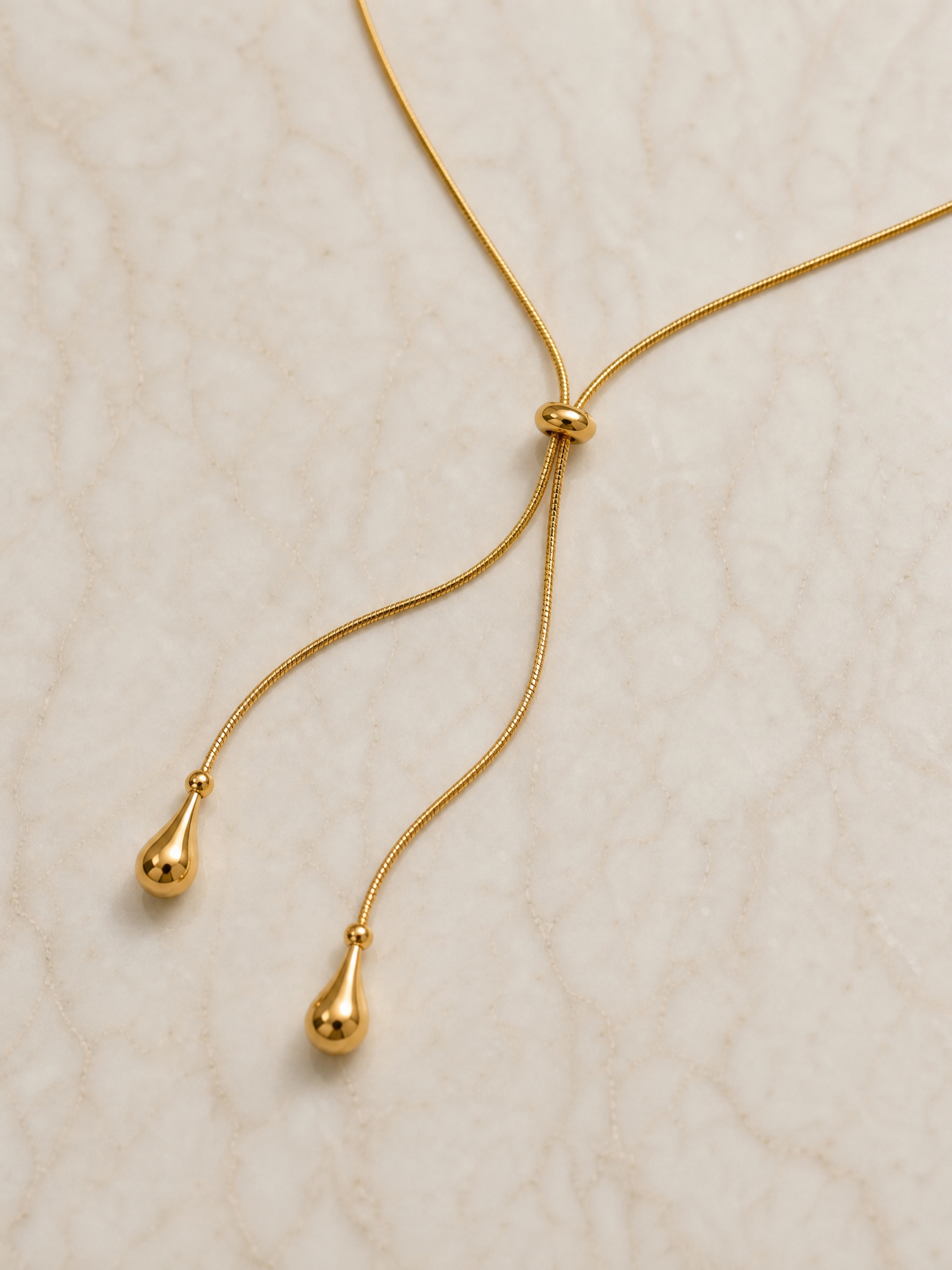 Macro du nœud coulissant et des deux gouttes dorées du collier Thaïs
